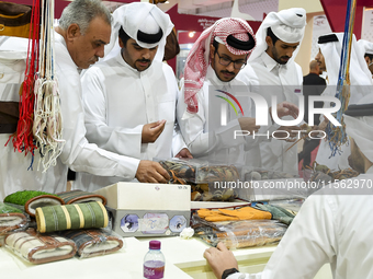 Qatari visitors visit a hunting accessories stall during the 8th edition of the Katara International Hunting and Falcons Exhibition 2024 (S'...