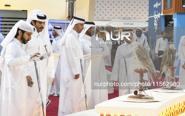 Visitors look at perched falcons while hooded during the 8th edition of the Katara International Hunting and Falcons Exhibition 2024 (S'hail...