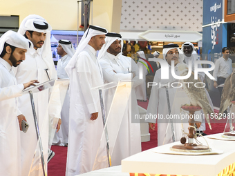 Visitors look at perched falcons while hooded during the 8th edition of the Katara International Hunting and Falcons Exhibition 2024 (S'hail...