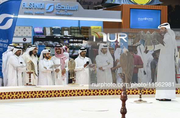 Visitors look at perched falcons while hooded during the 8th edition of the Katara International Hunting and Falcons Exhibition 2024 (S'hail...