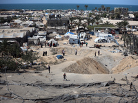 A Palestinian youth inspects the damage at the site of Israeli strikes on a makeshift displacement camp in Mawasi Khan Yunis in the Gaza Str...