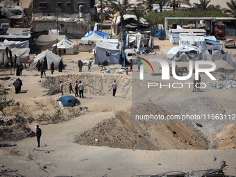 A Palestinian youth inspects the damage at the site of Israeli strikes on a makeshift displacement camp in Mawasi Khan Yunis in the Gaza Str...