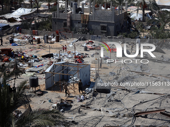 A Palestinian youth inspects the damage at the site of Israeli strikes on a makeshift displacement camp in Mawasi Khan Yunis in the Gaza Str...