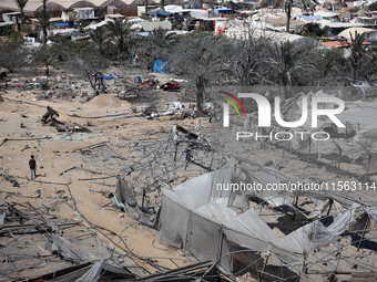 A Palestinian youth inspects the damage at the site of Israeli strikes on a makeshift displacement camp in Mawasi Khan Yunis in the Gaza Str...