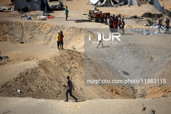 A Palestinian youth inspects the damage at the site of Israeli strikes on a makeshift displacement camp in Mawasi Khan Yunis in the Gaza Str...