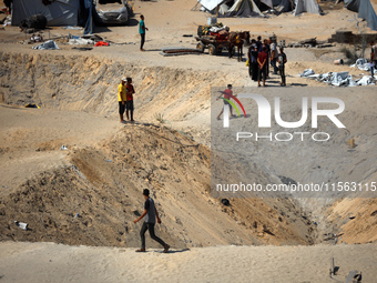 A Palestinian youth inspects the damage at the site of Israeli strikes on a makeshift displacement camp in Mawasi Khan Yunis in the Gaza Str...