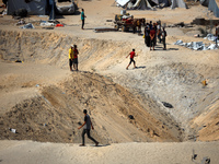 A Palestinian youth inspects the damage at the site of Israeli strikes on a makeshift displacement camp in Mawasi Khan Yunis in the Gaza Str...