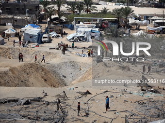 A Palestinian youth inspects the damage at the site of Israeli strikes on a makeshift displacement camp in Mawasi Khan Yunis in the Gaza Str...