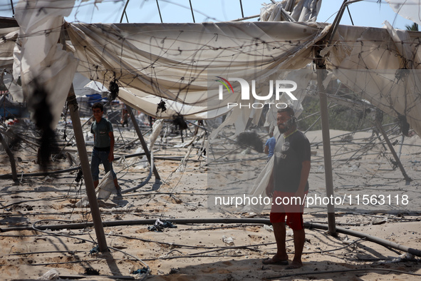 Palestinians inspect the damage at the site of Israeli strikes on a makeshift displacement camp in Mawasi Khan Yunis in the Gaza Strip on Se...