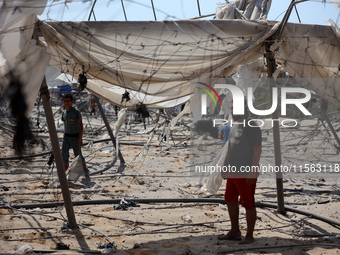 Palestinians inspect the damage at the site of Israeli strikes on a makeshift displacement camp in Mawasi Khan Yunis in the Gaza Strip on Se...