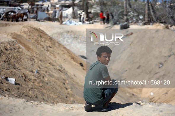 Palestinians inspect the damage at the site of Israeli strikes on a makeshift displacement camp in Mawasi Khan Yunis in the Gaza Strip on Se...