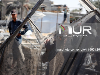 A Palestinian youth inspects the damage at the site of Israeli strikes on a makeshift displacement camp in Mawasi Khan Yunis in the Gaza Str...