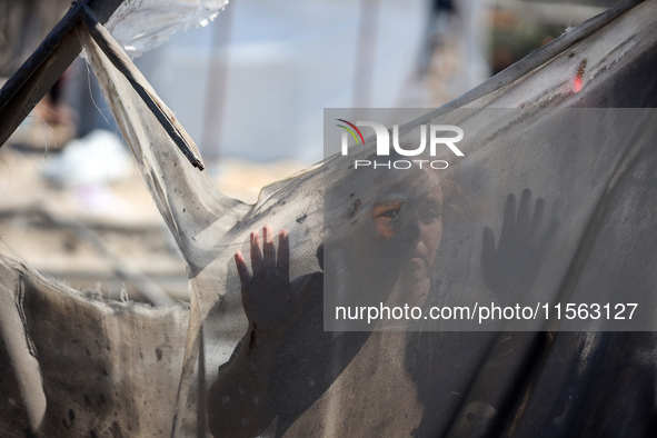 A Palestinian youth inspects the damage at the site of Israeli strikes on a makeshift displacement camp in Mawasi Khan Yunis in the Gaza Str...