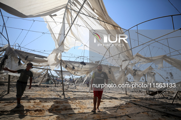 Palestinians inspect the damage at the site of Israeli strikes on a makeshift displacement camp in Mawasi Khan Yunis in the Gaza Strip on Se...