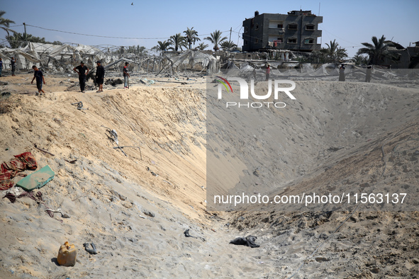 Palestinians inspect the damage at the site of Israeli strikes on a makeshift displacement camp in Mawasi Khan Yunis in the Gaza Strip on Se...