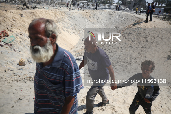 Palestinians inspect the damage at the site of Israeli strikes on a makeshift displacement camp in Mawasi Khan Yunis in the Gaza Strip on Se...