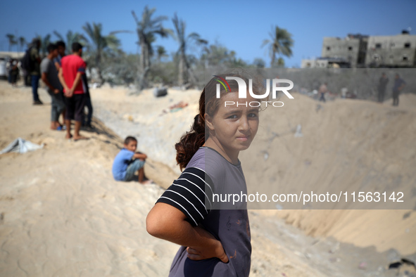 Palestinians inspect the damage at the site of Israeli strikes on a makeshift displacement camp in Mawasi Khan Yunis in the Gaza Strip on Se...