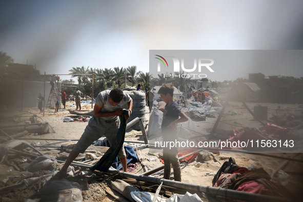 Palestinians inspect the damage at the site of Israeli strikes on a makeshift displacement camp in Mawasi Khan Yunis in the Gaza Strip on Se...