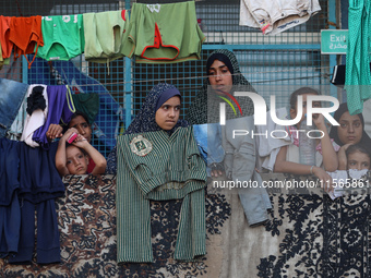 Displaced Palestinians take shelter at a UN school and watch after an Israeli air strike hits the site in Nuseirat, Gaza Strip, on September...