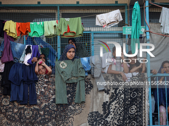 Displaced Palestinians take shelter at a UN school and watch after an Israeli air strike hits the site in Nuseirat, Gaza Strip, on September...