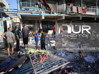 Palestinians check the grounds of a school after an Israeli air strike hits the site in Nuseirat, Gaza Strip, on September 11, 2024, amid th...