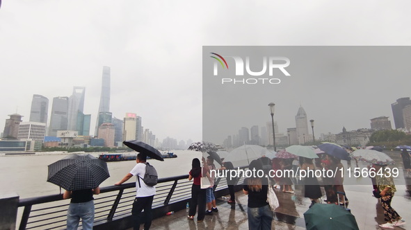 Tourists view the area amid heavy rain affected by a typhoon in Shanghai, China, on September 10, 2024. 