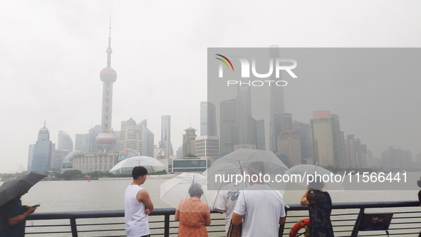 Tourists view the area amid heavy rain affected by a typhoon in Shanghai, China, on September 10, 2024. 