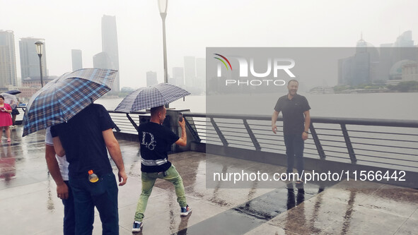 Tourists view the area amid heavy rain affected by a typhoon in Shanghai, China, on September 10, 2024. 