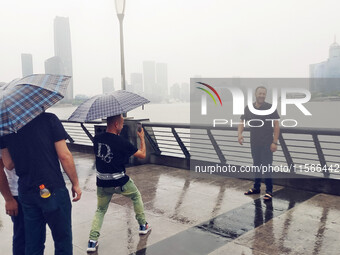 Tourists view the area amid heavy rain affected by a typhoon in Shanghai, China, on September 10, 2024. (