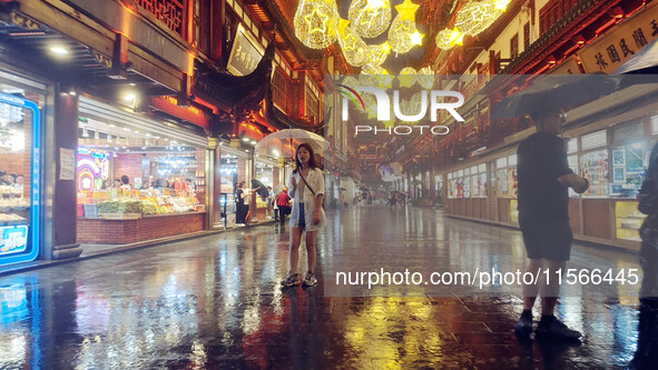 Tourists view the area amid heavy rain affected by a typhoon in Shanghai, China, on September 10, 2024. 