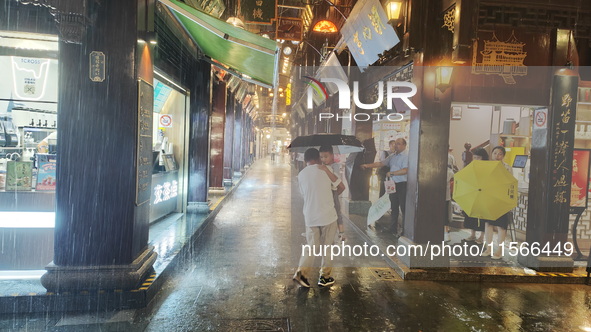 Tourists view the area amid heavy rain affected by a typhoon in Shanghai, China, on September 10, 2024. 