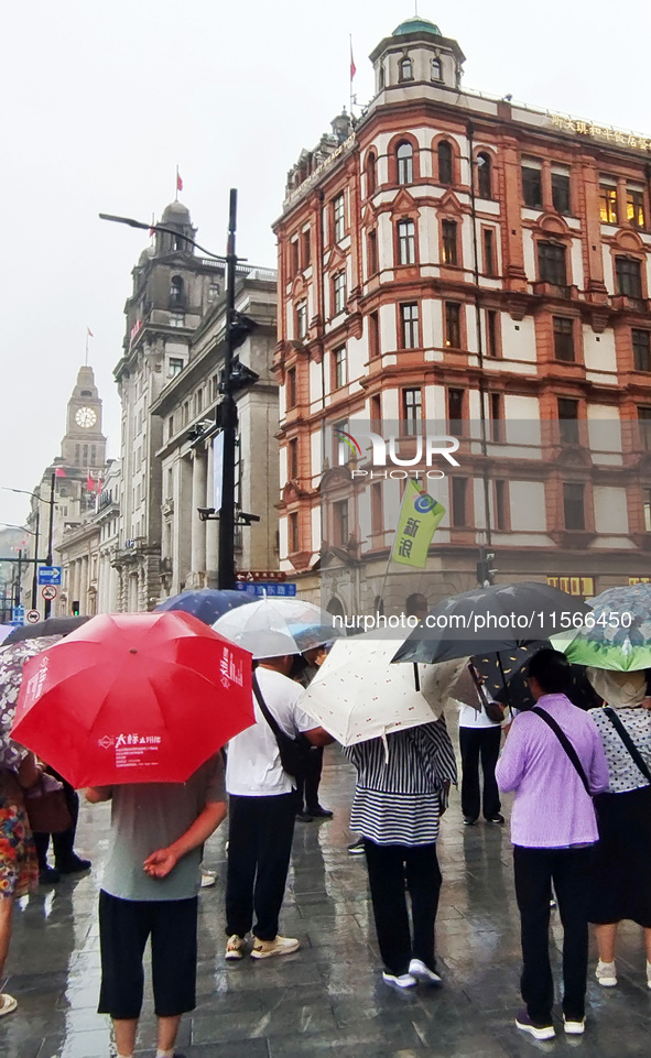 Tourists view the area amid heavy rain affected by a typhoon in Shanghai, China, on September 10, 2024. 