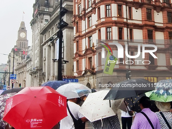 Tourists view the area amid heavy rain affected by a typhoon in Shanghai, China, on September 10, 2024. (