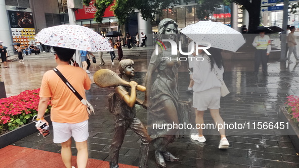 Tourists view the area amid heavy rain affected by a typhoon in Shanghai, China, on September 10, 2024. 