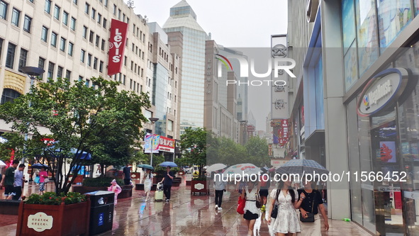 Tourists view the area amid heavy rain affected by a typhoon in Shanghai, China, on September 10, 2024. 