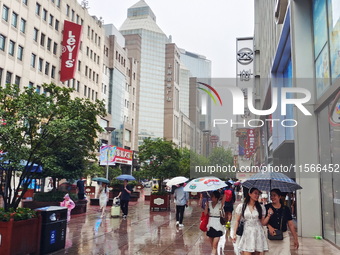 Tourists view the area amid heavy rain affected by a typhoon in Shanghai, China, on September 10, 2024. (