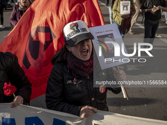 A person carries a photograph of a disappeared detainee in a march commemorating the 51st anniversary of the coup in Chile. (