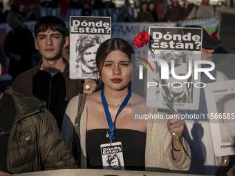 A person carries a photograph of a disappeared detainee in a march commemorating the 51st anniversary of the coup in Chile. (