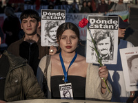 A person carries a photograph of a disappeared detainee in a march commemorating the 51st anniversary of the coup in Chile. (