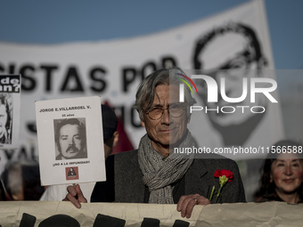 A person carries a photograph of a disappeared detainee in a march commemorating the 51st anniversary of the coup in Chile. (