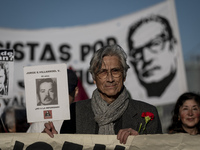 A person carries a photograph of a disappeared detainee in a march commemorating the 51st anniversary of the coup in Chile. (