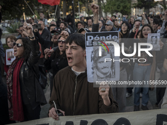 A person carries a photograph of a disappeared detainee in a march commemorating the 51st anniversary of the coup in Chile. (