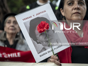 A person carries a photograph of a disappeared detainee in a march commemorating the 51st anniversary of the coup in Chile. (