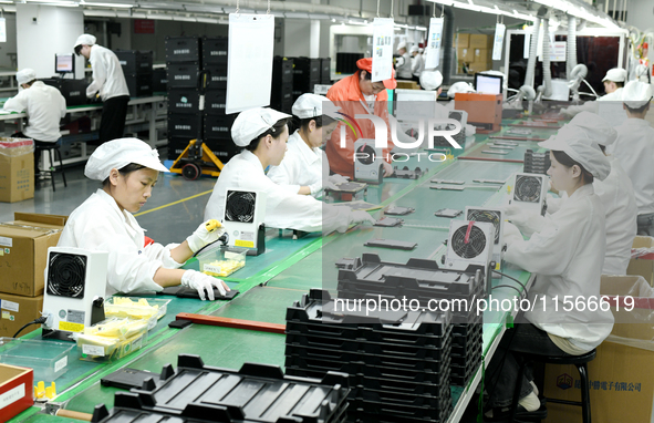 Workers rush to make computer and tablet battery orders at a workshop in Hai'an, China, on September 11, 2024. 