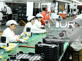 Workers rush to make computer and tablet battery orders at a workshop in Hai'an, China, on September 11, 2024. (