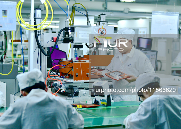 Workers rush to make computer and tablet battery orders at a workshop in Hai'an, China, on September 11, 2024. 