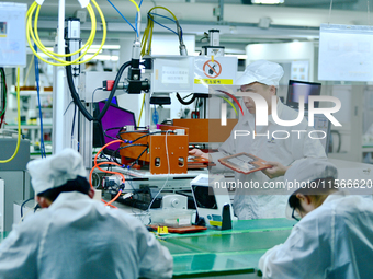 Workers rush to make computer and tablet battery orders at a workshop in Hai'an, China, on September 11, 2024. (