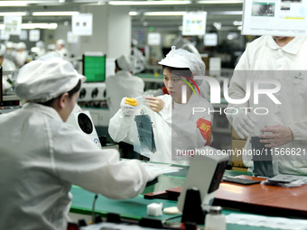 Workers rush to make computer and tablet battery orders at a workshop in Hai'an, China, on September 11, 2024. (