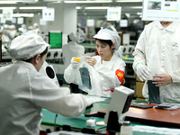 Workers rush to make computer and tablet battery orders at a workshop in Hai'an, China, on September 11, 2024. (