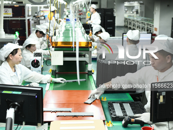 Workers rush to make computer and tablet battery orders at a workshop in Hai'an, China, on September 11, 2024. (